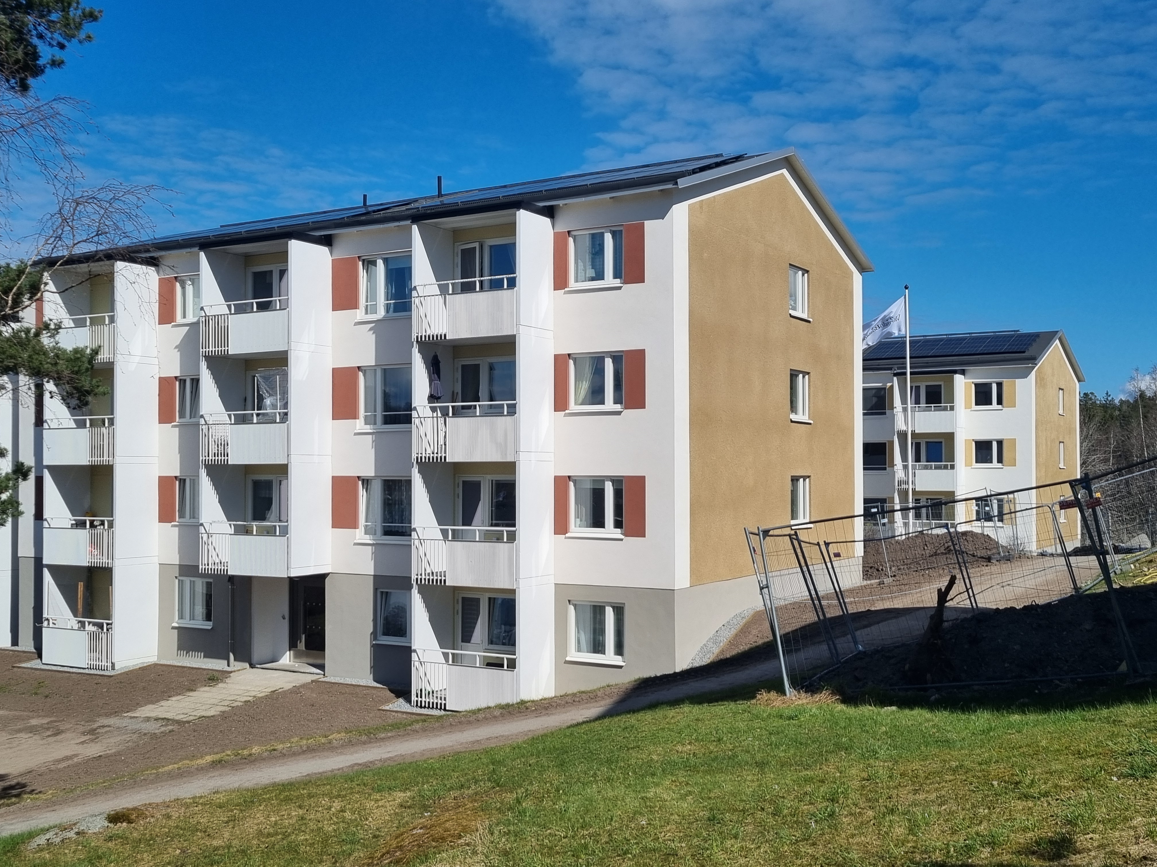 Bild på två hus tagna strax efter renovering. Byggstaket på gården.