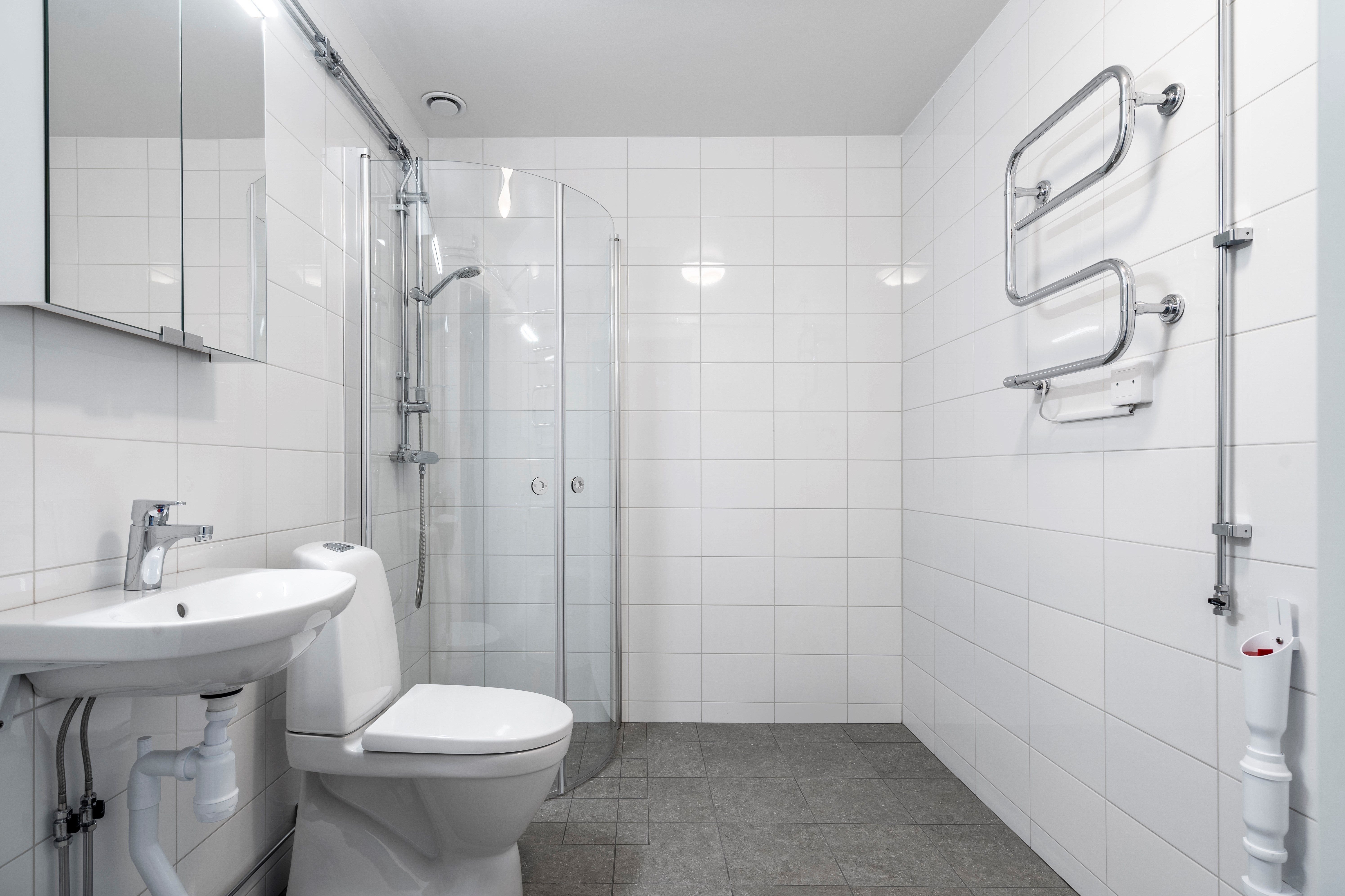 Nyrenoverat badrum med vitt kakel och grått golv