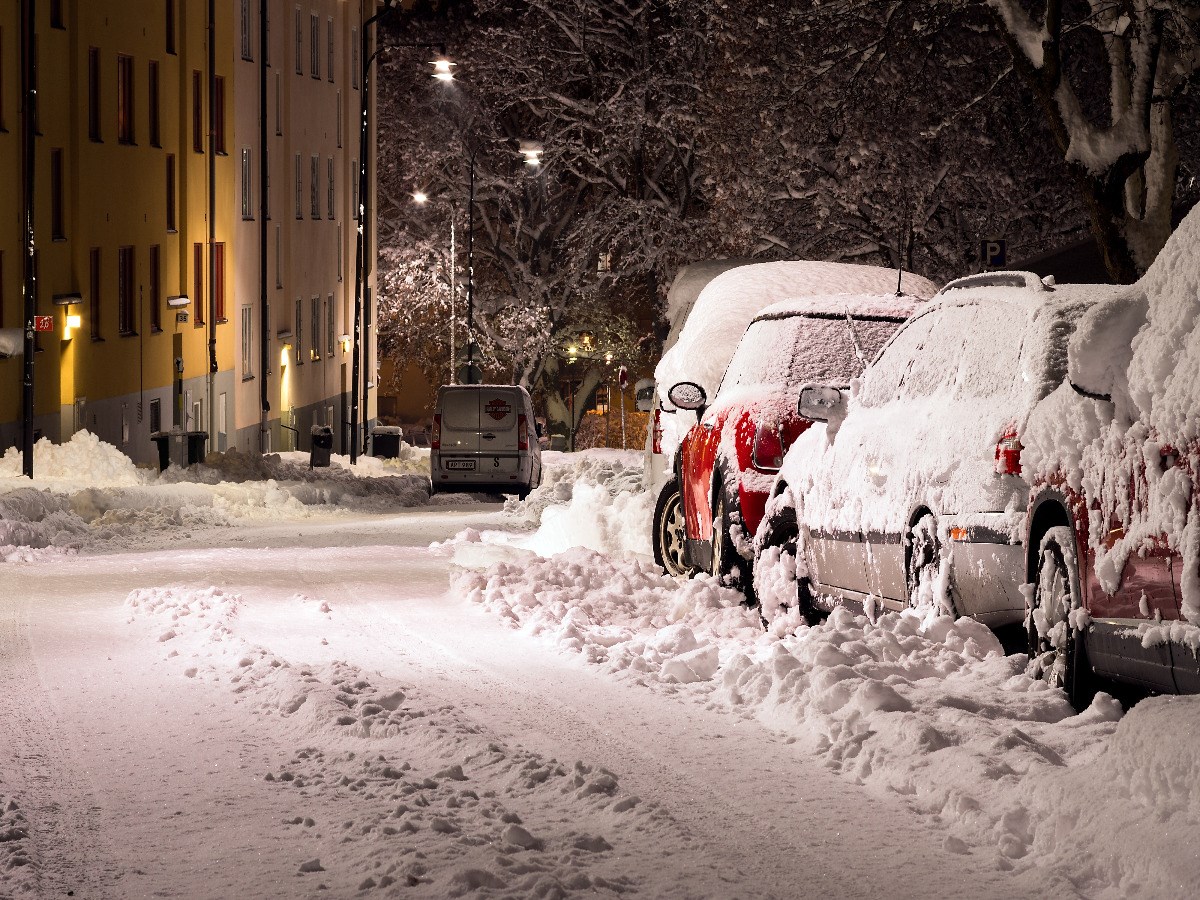 Snötäckt gata med parkerade bilar