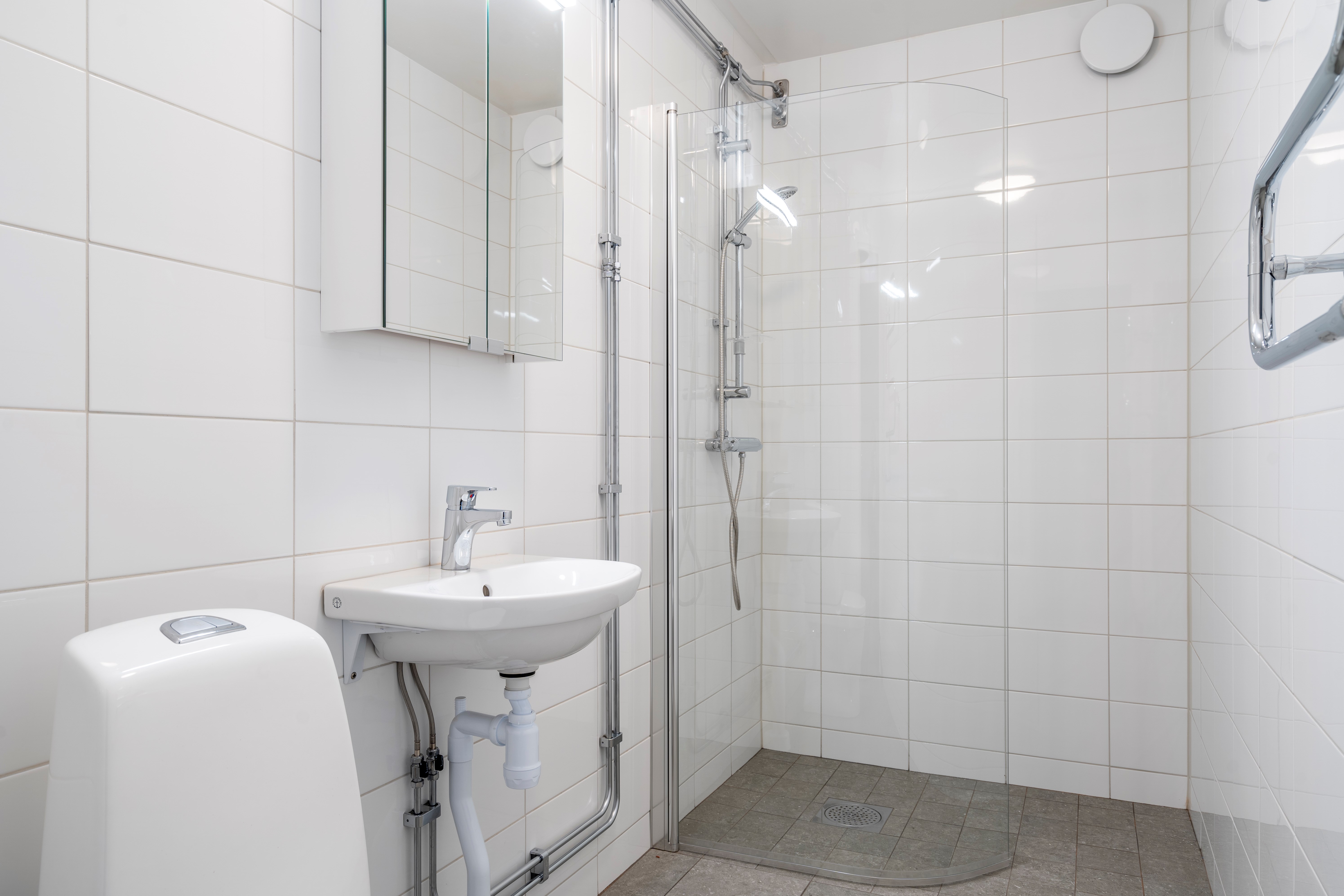 Nyrenoverat badrum med vitt kakel och grått golv