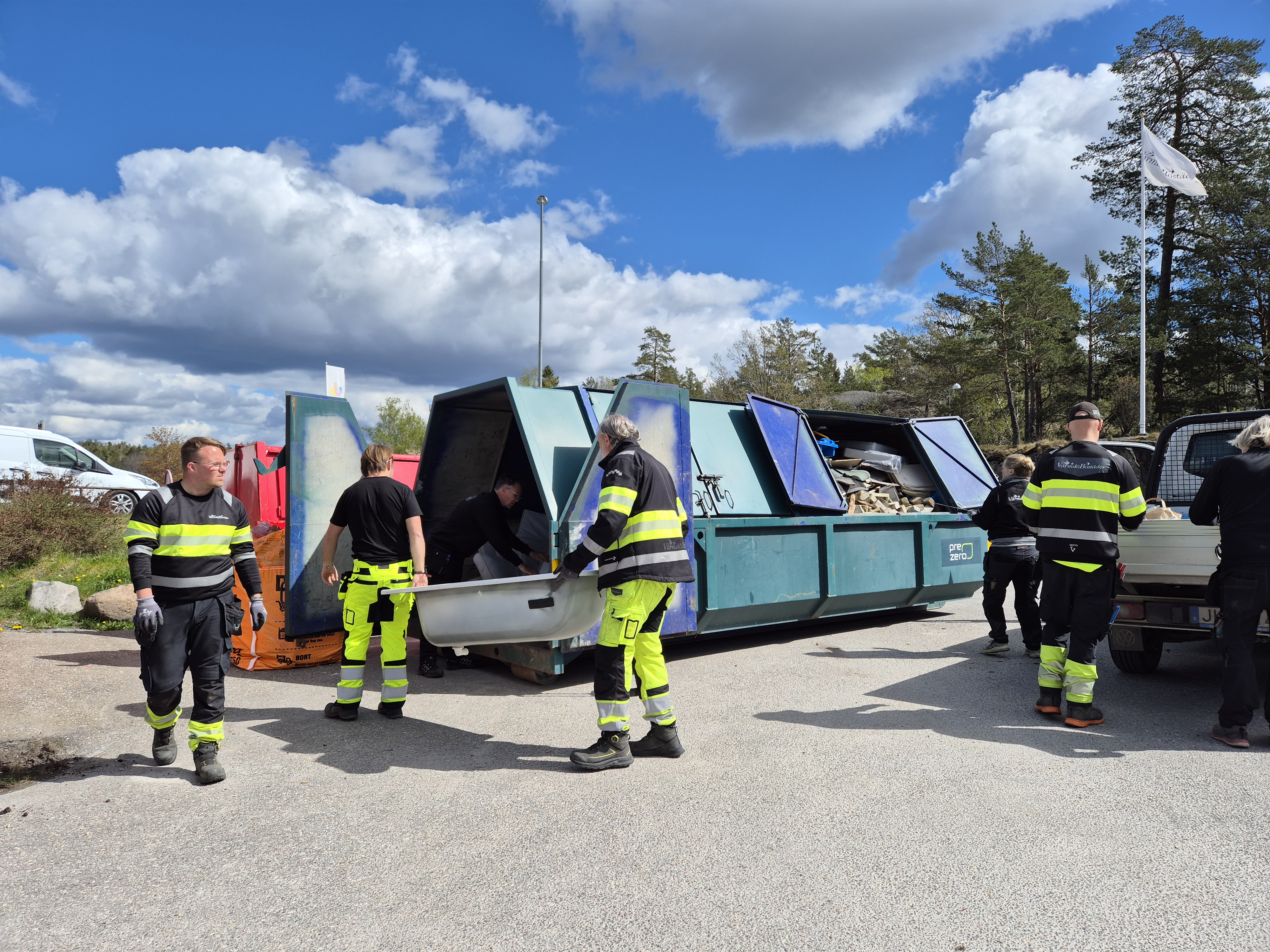 Personal från VärmdörBostäder som slänger skräp i en grön container