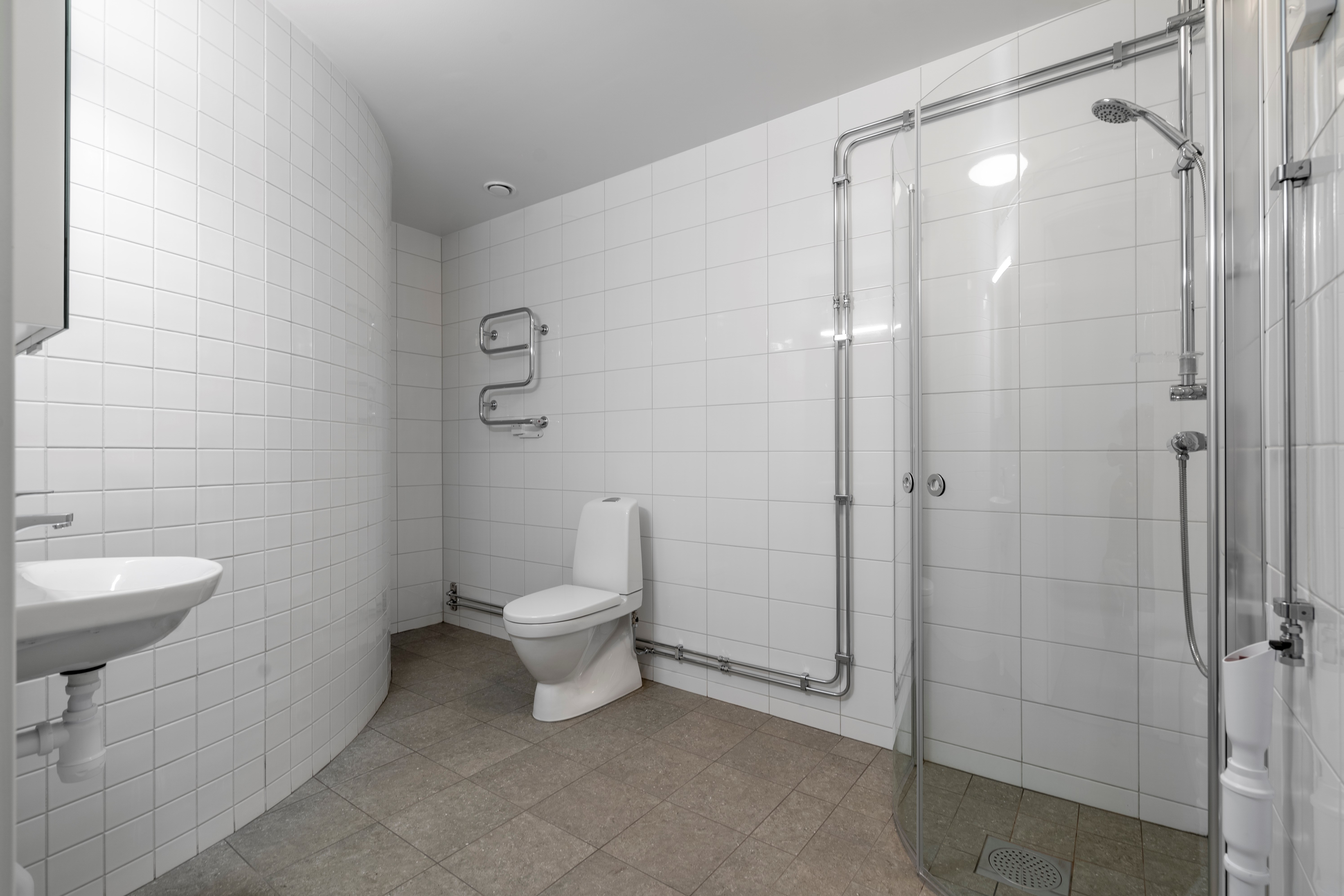 Nyrenoverat badrum med vitt kakel och grått golv