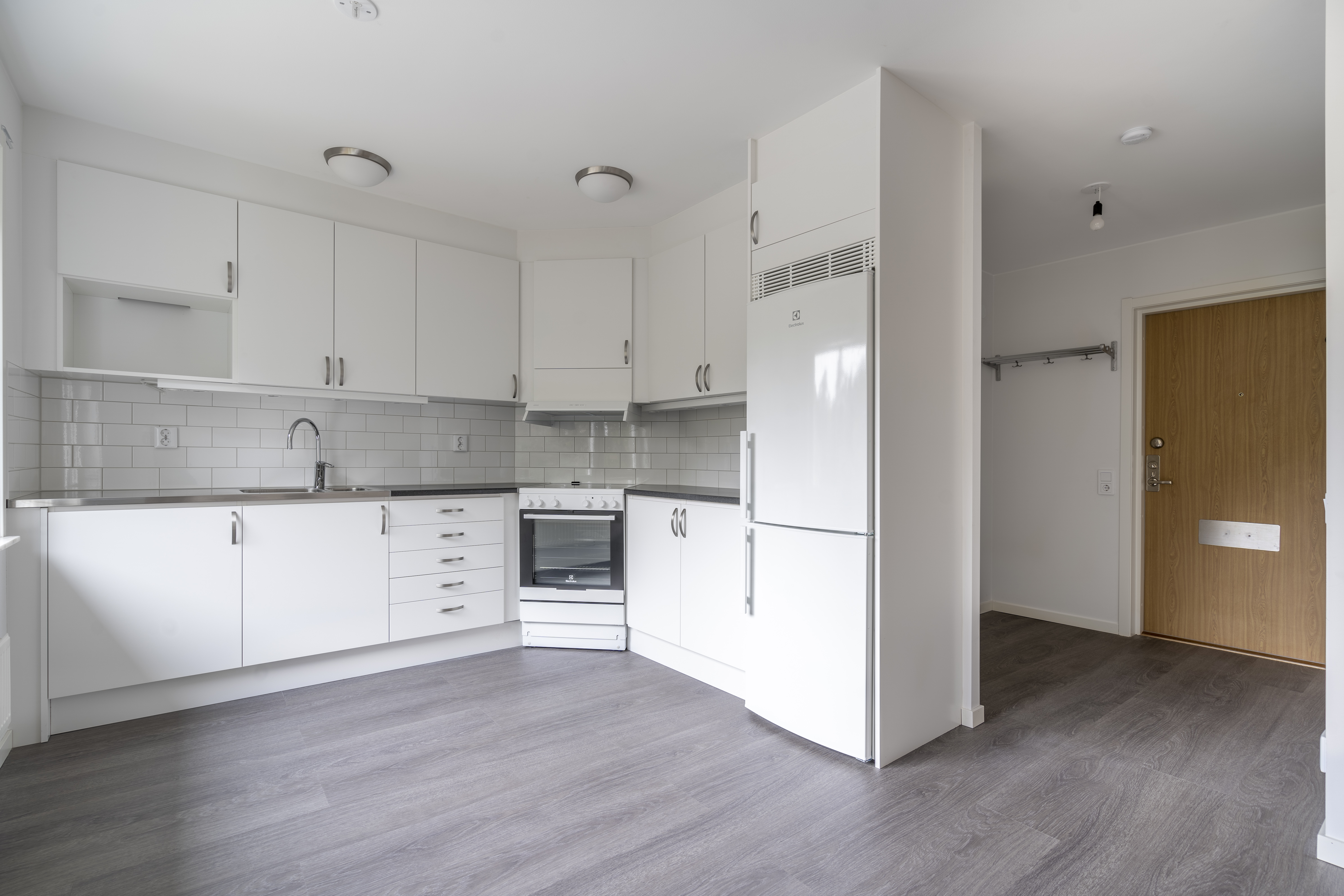 Nyrenoverat kök ,ed vita luckor, nytt golv. hall synlig i bakgrunden.